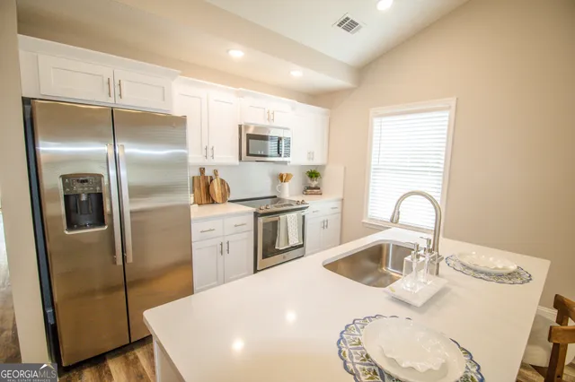 a kitchen with stainless steel appliances a refrigerator a sink a stove and cabinets