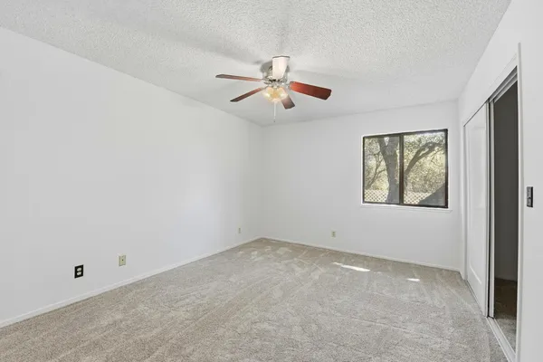 an empty room with windows and fan