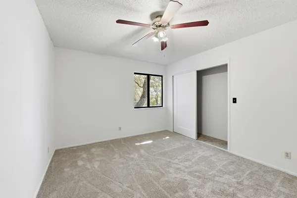 an empty room with windows and fan