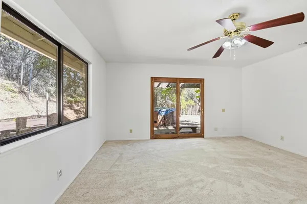 an empty room with windows and fan