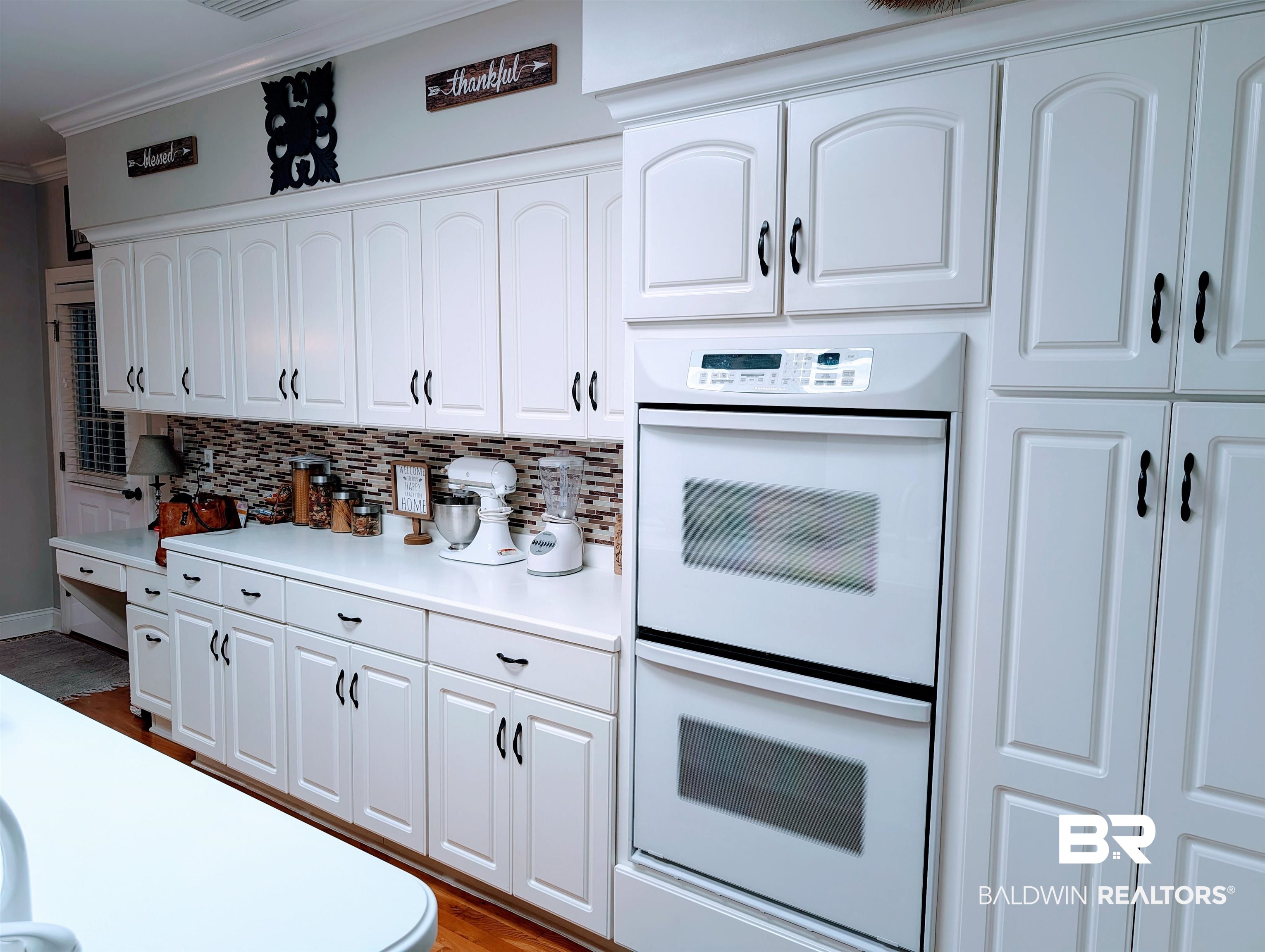 506 Old Castleberry Road Brewton, AL 36426 - Photo 7 of 14 Kitchen featuring backsplash, white cabinets, white double oven, and crown molding