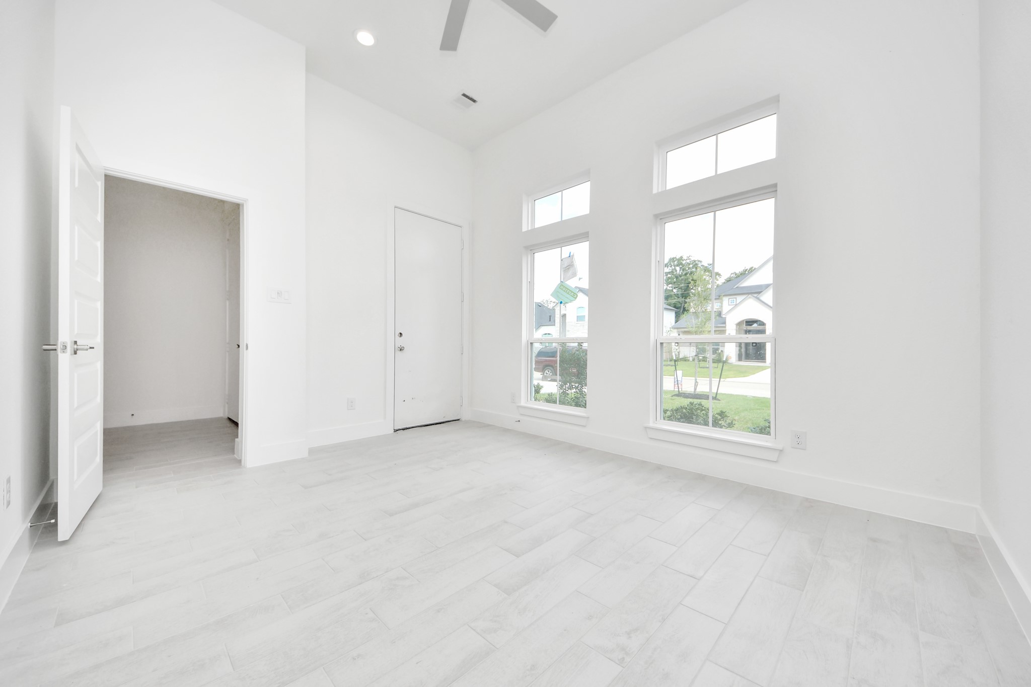 Experience the perfect blend of sophistication and warmth in this home office, boasting elegant wood-look tile flooring and flooded with natural light from expansive windows and French doors.