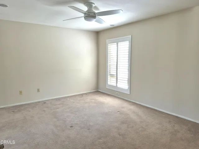 an empty room with a window and ceiling fan