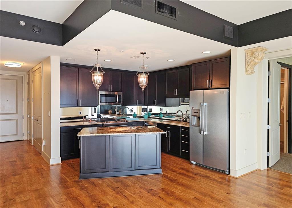 4561 Olde Perimeter Way, Unit 704 Atlanta, GA 30346 - Photo 5 of 45 a kitchen with stainless steel appliances granite countertop a refrigerator a sink dishwasher a stove and white countertops with wooden floor