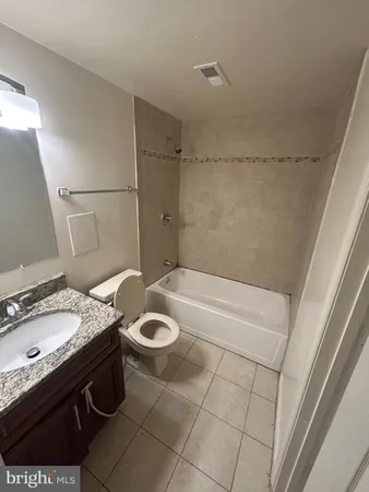 a bathroom with a granite countertop sink a toilet and bathtub