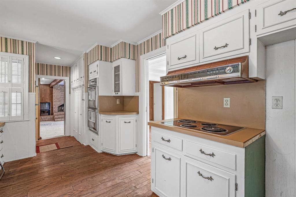 1222 Kentucky Street Graham, TX 76450 - Photo 11 of 37 a kitchen with granite countertop a stove cabinets and wooden floor