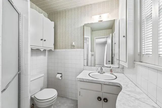 a view of an empty room with window and chandelier fan