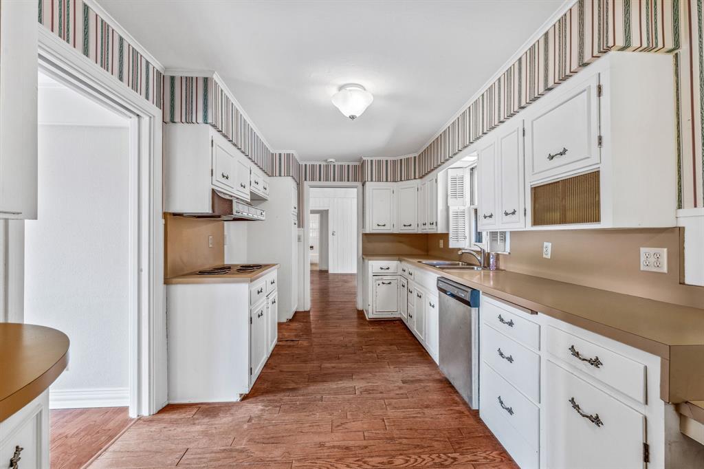 1222 Kentucky Street Graham, TX 76450 - Photo 10 of 37 a kitchen with granite countertop a sink a counter top space stainless steel appliances and cabinets