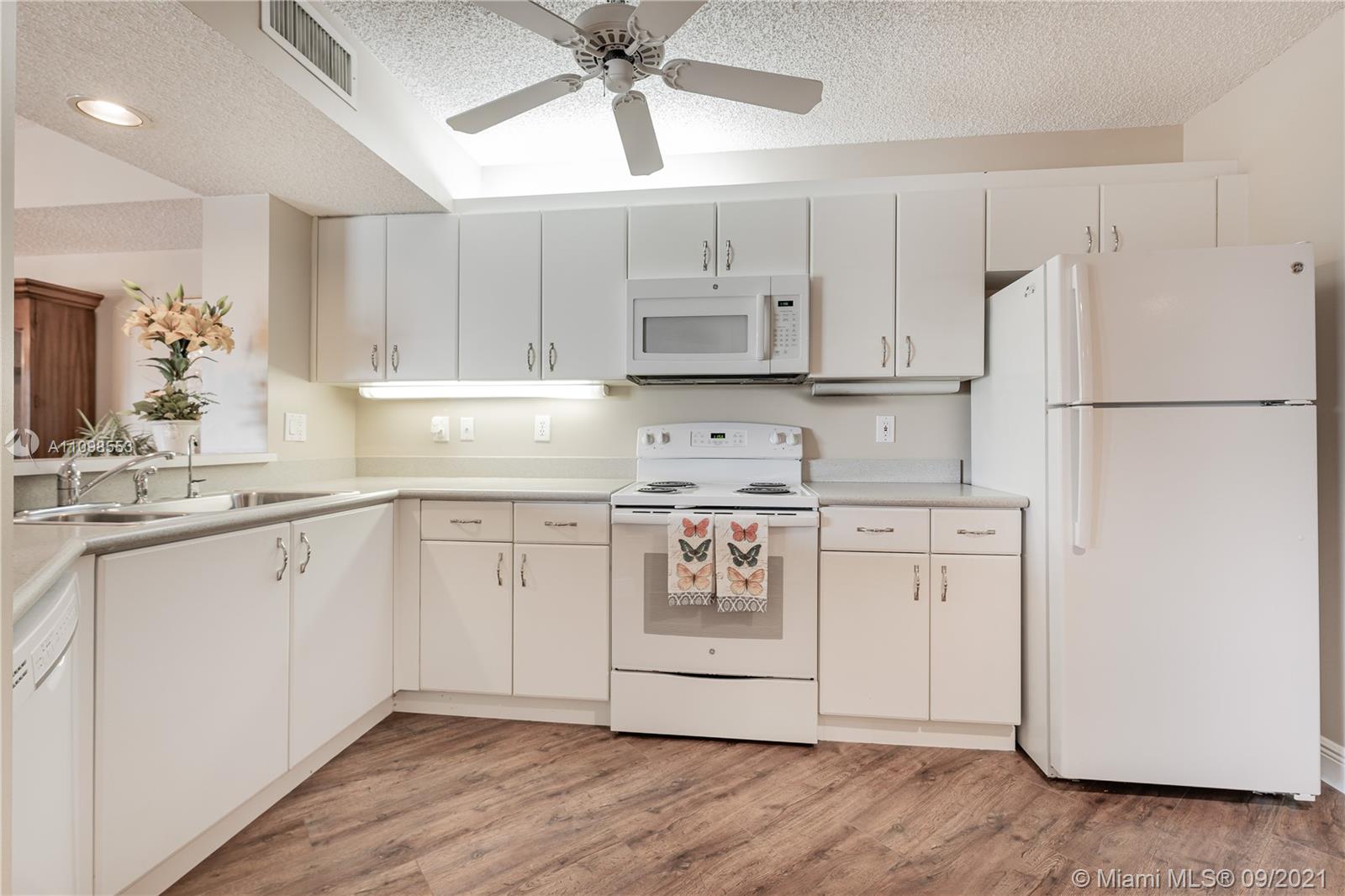 9563 Weldon Circle, Unit D207 Tamarac, FL 33321 - Photo 16 of 40 a kitchen with cabinets appliances wooden floor and a window