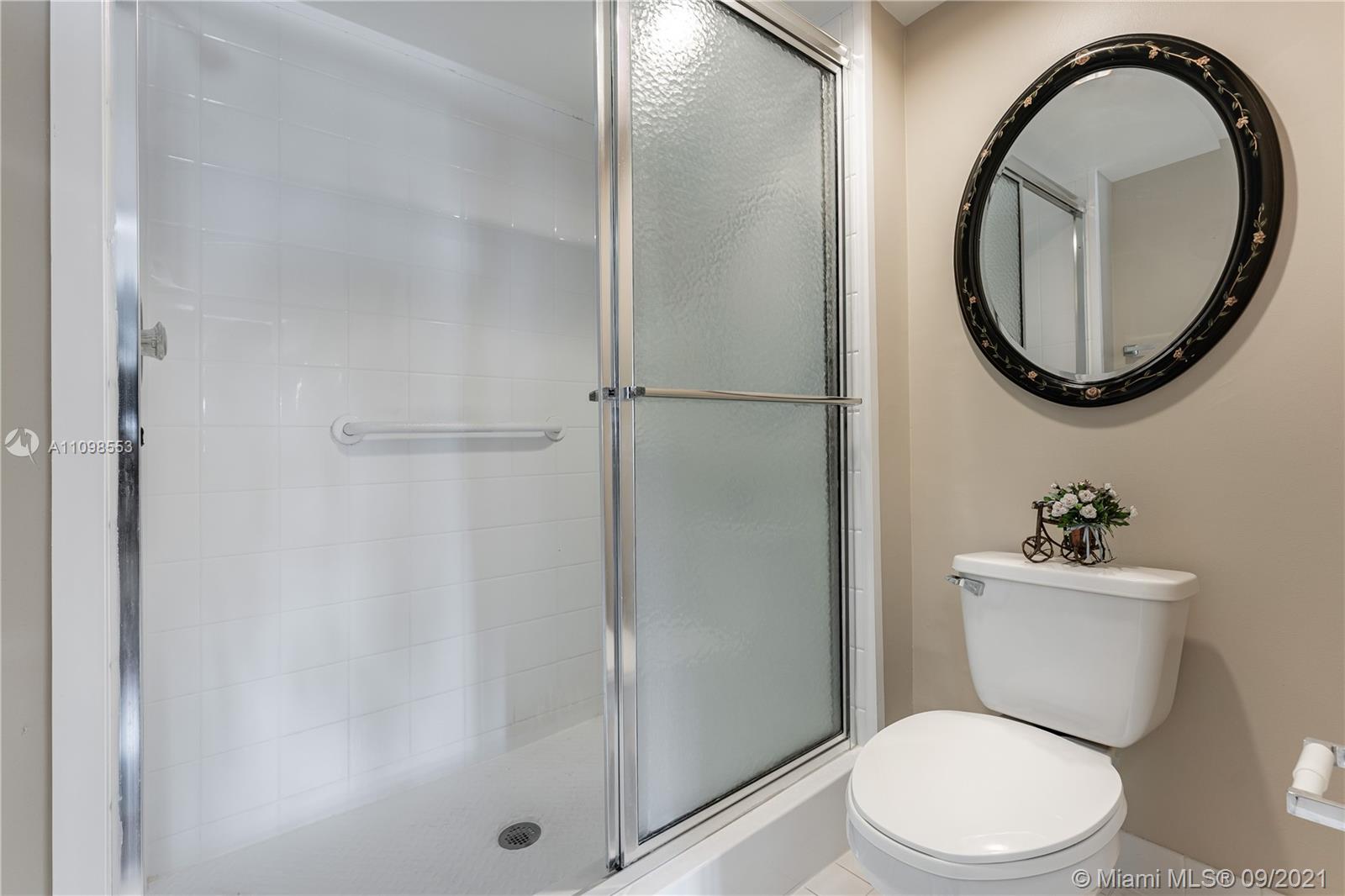 9563 Weldon Circle, Unit D207 Tamarac, FL 33321 - Photo 33 of 40 a white toilet sitting next to a bathroom sink and a mirror