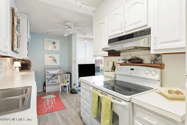 a kitchen that has a sink and a stove with wooden floor