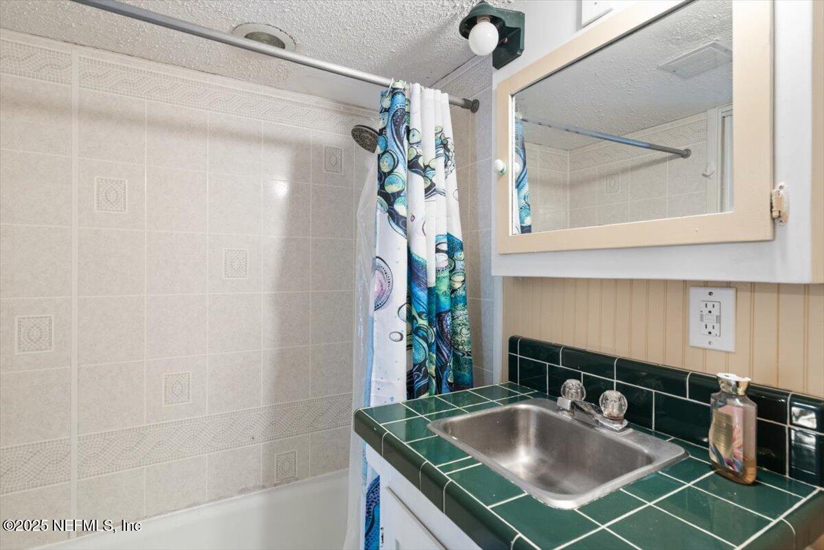 901 Ocean Boulevard, Unit 1 Atlantic Beach, FL 32233 - Photo 31 of 39 a bathroom with a granite countertop sink a mirror and a shower