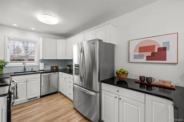 a kitchen with stainless steel appliances a refrigerator sink and wooden floor