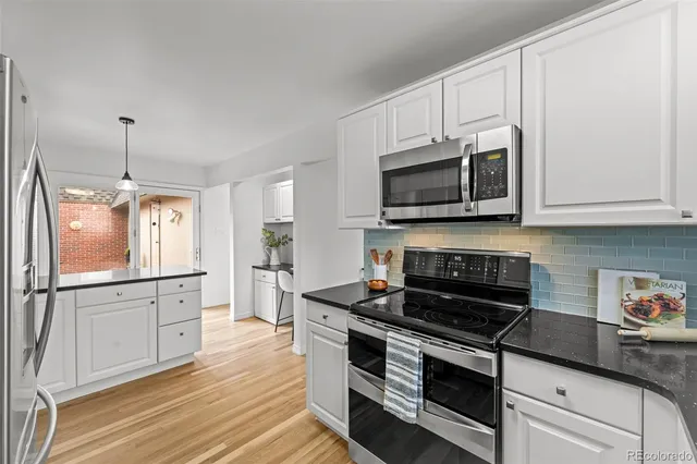 a kitchen with stainless steel appliances granite countertop white cabinets granite counter tops and a wooden floors