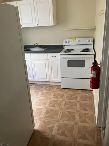 a kitchen with granite countertop white cabinets and white appliances