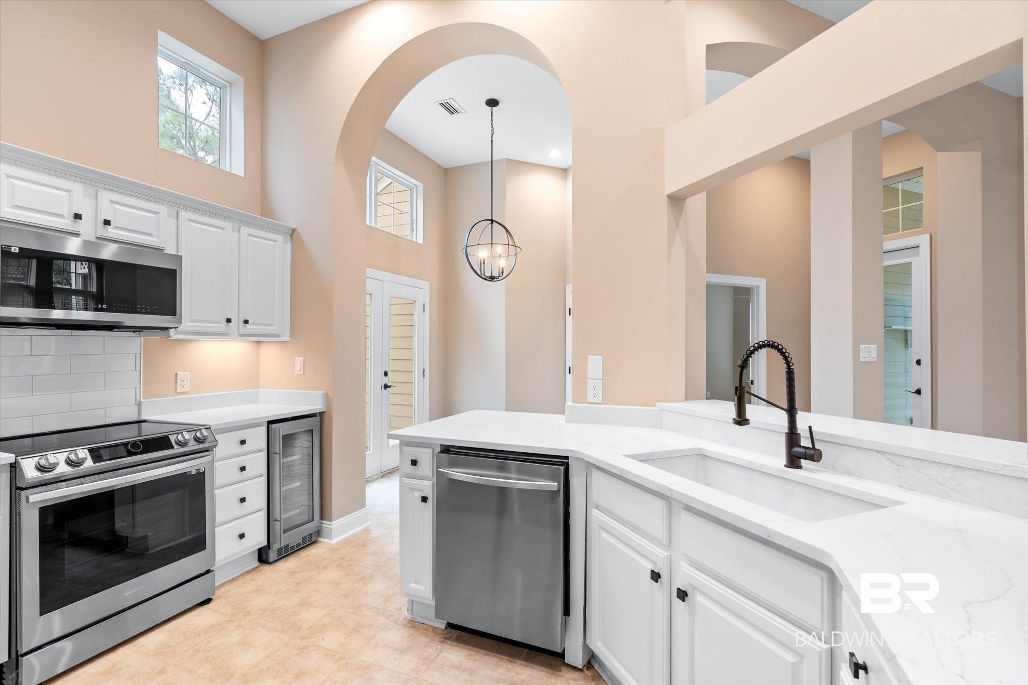 9259 Genipa Way Gulf Shores, AL 36542 - Photo 12 of 72 Kitchen with a towering ceiling, white cabinetry, appliances with stainless steel finishes, decorative light fixtures, and wine cooler
