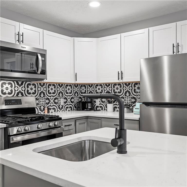 1117-1119 Spring Garden Avenue Pittsburgh, PA 15212 - Photo 12 of 27 a kitchen with stainless steel appliances granite countertop a sink a stove and a refrigerator