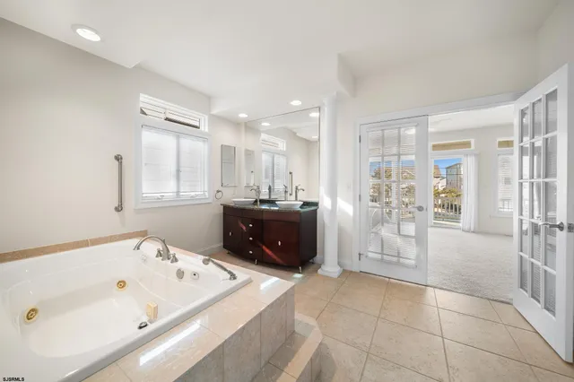 a large bathroom with a tub a double vanity sink and glass door