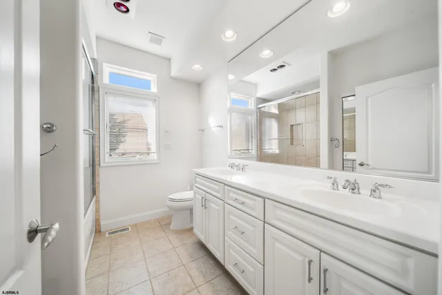 a spacious bathroom with a double vanity sink a mirror and a toilet