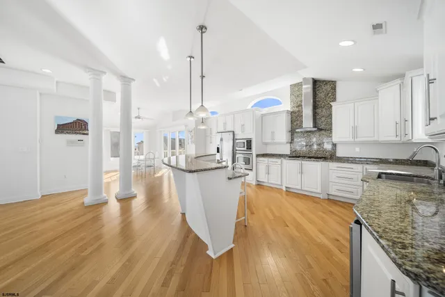 a view of a kitchen with kitchen island granite countertop wooden floor stainless steel appliances and cabinets