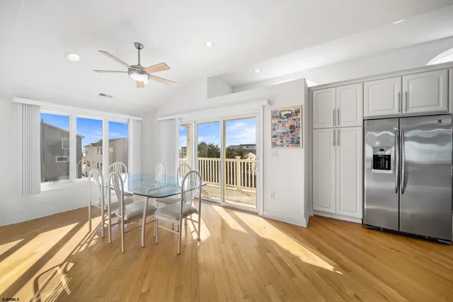a view of a dining room with furniture a ceiling fan and wooden floor
