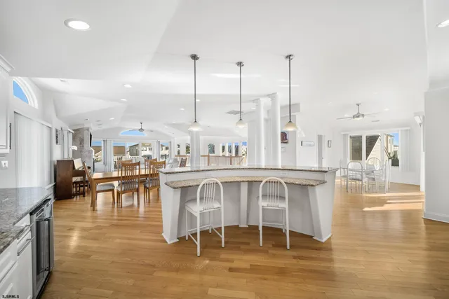 a dining hall with stainless steel appliances kitchen island granite countertop a table chairs and a view of living room