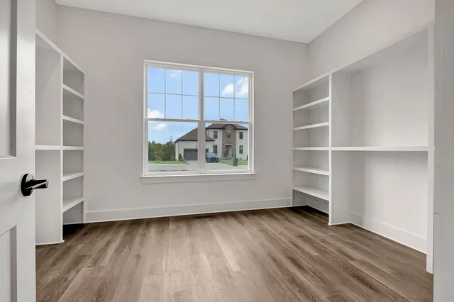 a view of an empty room with a window and wooden floor