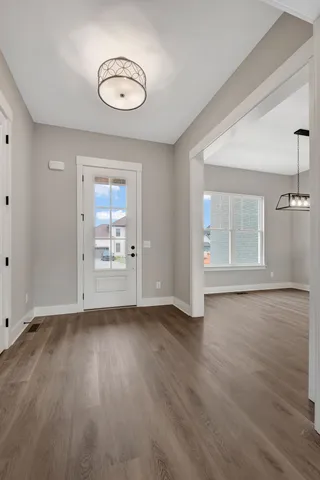 an empty room with wooden floor cabinet and windows