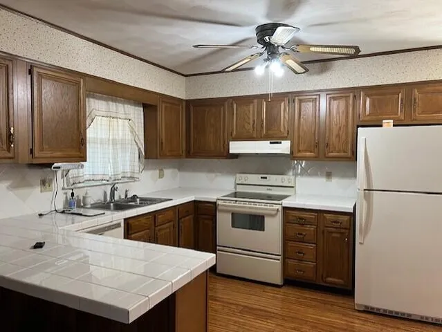 a kitchen with a sink a stove a refrigerator cabinets and wooden floor