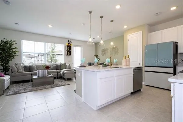 a living room with furniture a chandelier and kitchen view