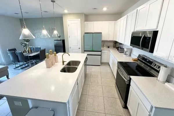 a kitchen with stainless steel appliances kitchen island granite countertop a refrigerator a stove a sink a dining table and chairs with wooden floor