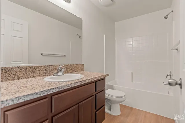 a bathroom with a granite countertop sink a toilet and shower