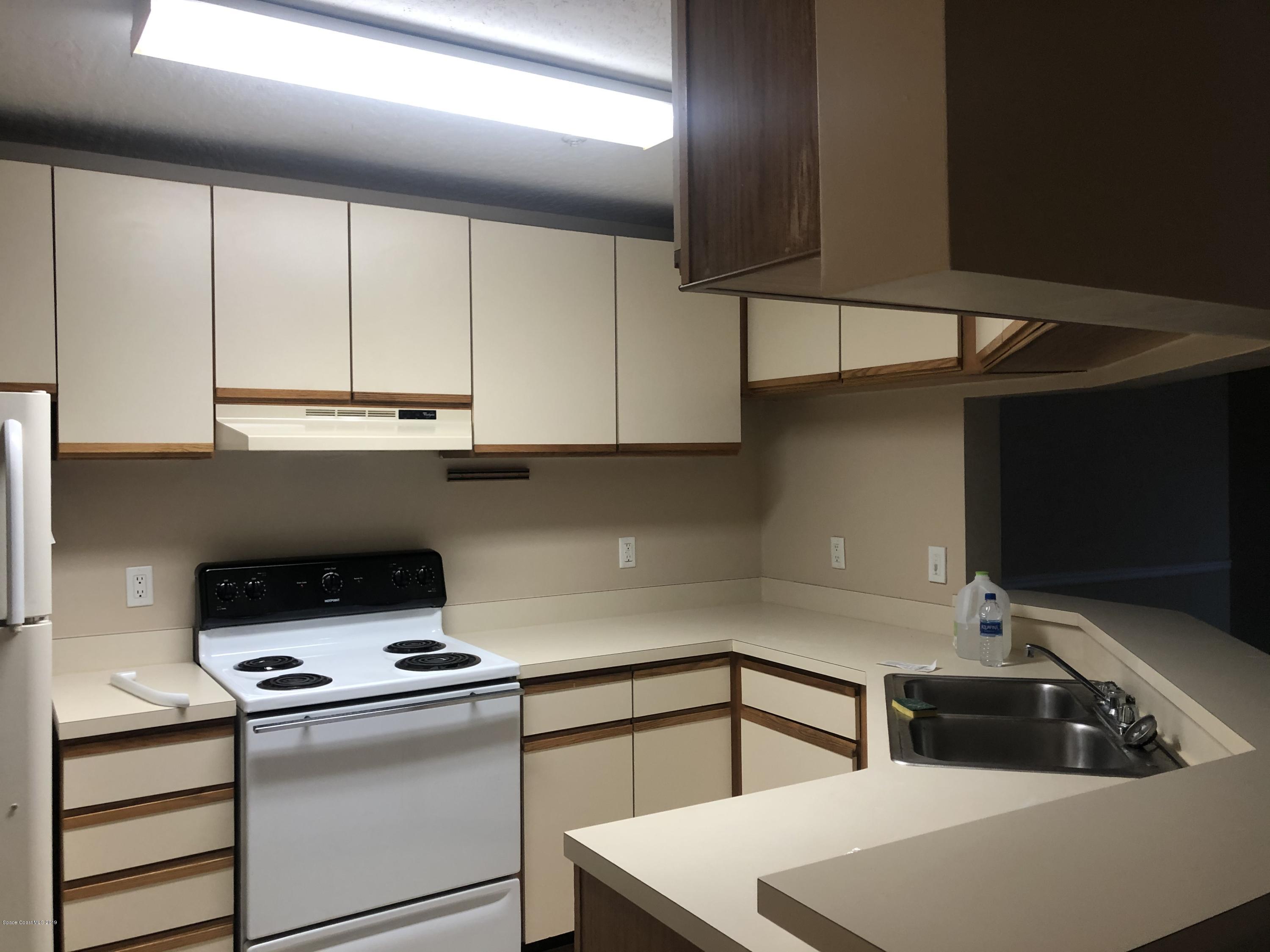 7667 North Wickham Road, Unit 915 Melbourne, FL 32940 - Photo 4 of 12 a kitchen with stainless steel appliances a stove a sink and white cabinets