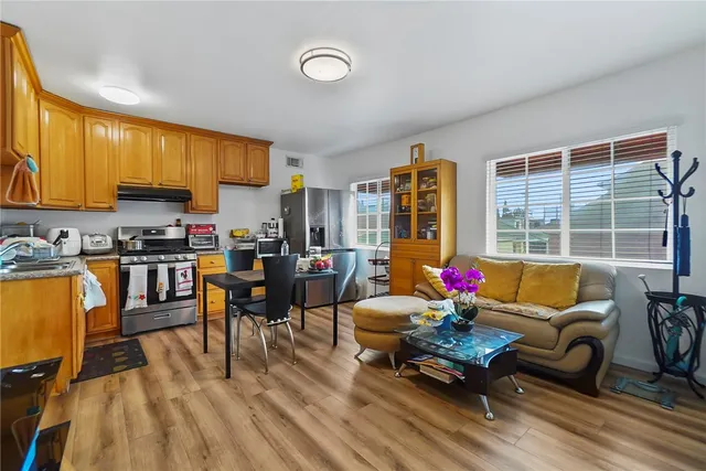 a kitchen with stainless steel appliances kitchen island granite countertop a refrigerator oven a stove top oven and a dining table