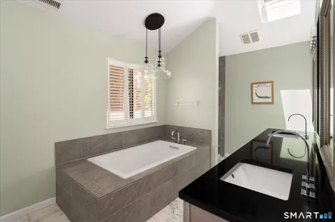 a bathroom with a sink a bathtub and a window