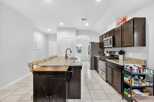 a kitchen with stainless steel appliances kitchen island granite countertop a sink a stove a microwave a counter top and cabinets