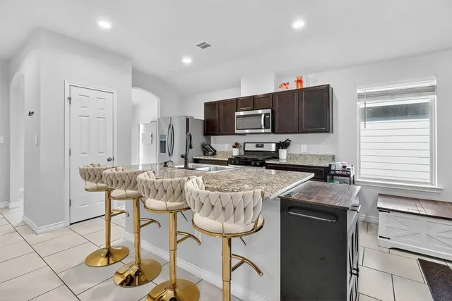 a kitchen with stainless steel appliances granite countertop a stove a sink a microwave a refrigerator and cabinets