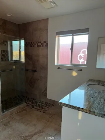 a bathroom with a granite countertop sink a mirror and shower