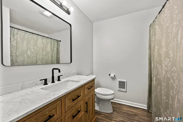a bathroom with a granite countertop toilet sink and mirror