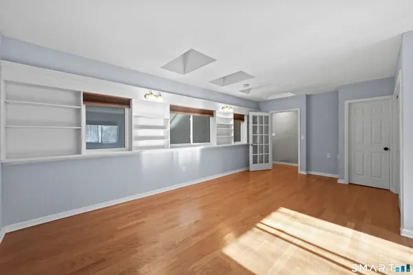 a view of an empty room with window and wooden floor