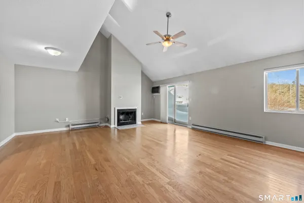 a view of an empty room with wooden floor and fireplace
