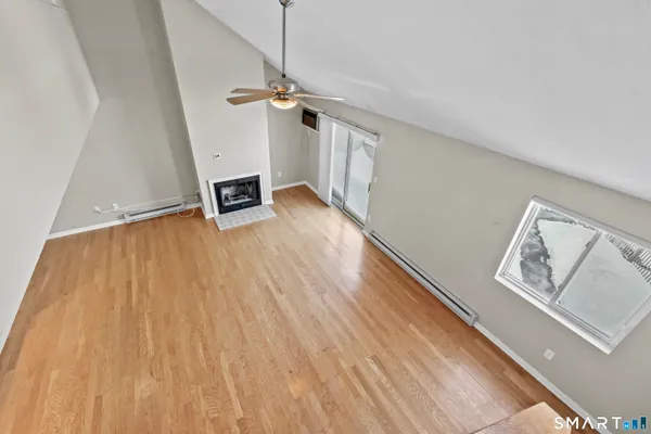 a view of an empty room with wooden floor and a ceiling fan