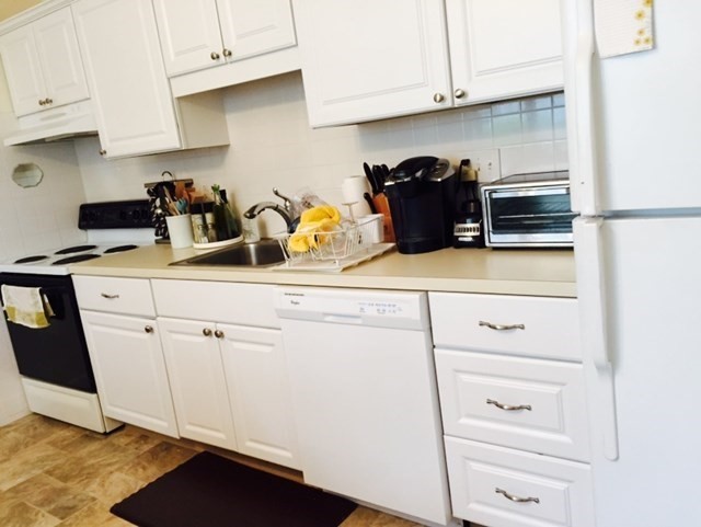 a kitchen with white cabinets and appliances
