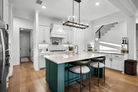 a kitchen with stainless steel appliances a center island wooden floor a large window and cabinets