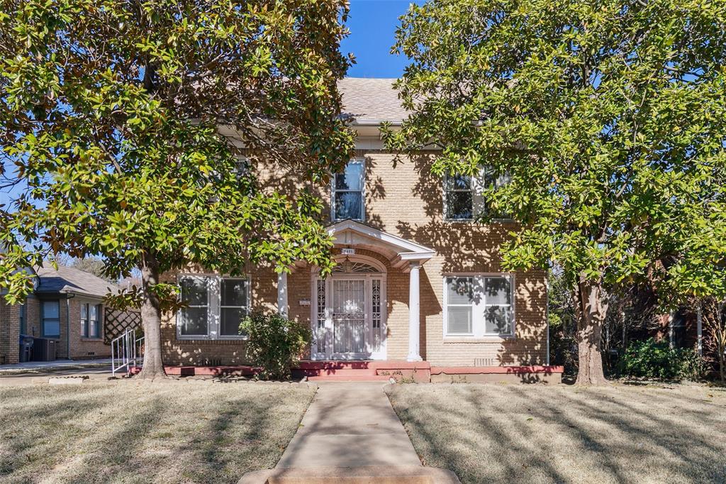 a front view of a house with a tree