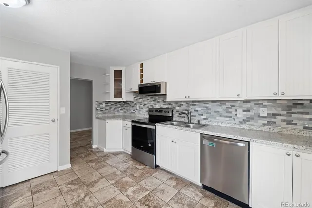 a kitchen with granite countertop a sink stove and cabinets