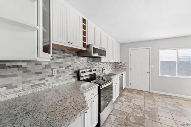 a kitchen with stainless steel appliances granite countertop a stove a sink and a microwave