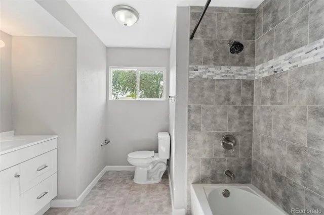 a bathroom with a granite countertop sink a toilet and shower