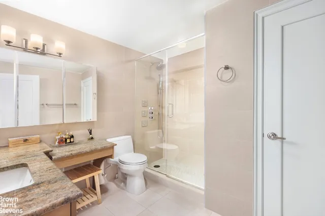 a bathroom with a granite countertop sink toilet a mirror and shower