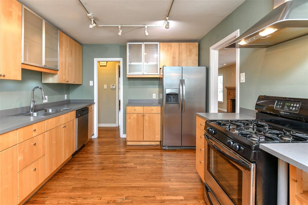 3516 Rashti Court Fort Worth, TX 76109 - Photo 11 of 24 Kitchen featuring rail lighting, stainless steel appliances, sink, wall chimney range hood, and light hardwood / wood-style floors